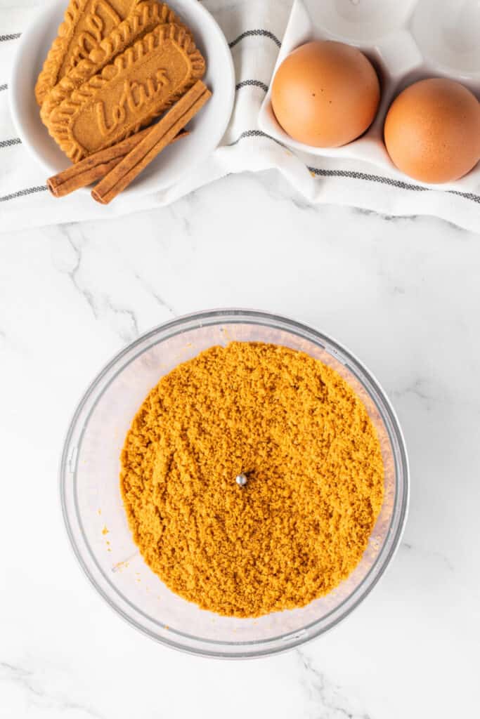 Finely crushed Biscoff cookie crumbs in a food processor for making mini pumpkin cheesecake crusts.
