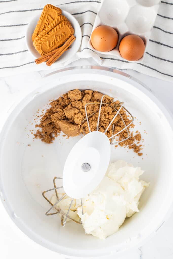 Cream cheese and brown sugar in a mixing bowl for making pumpkin cheesecake filling.
