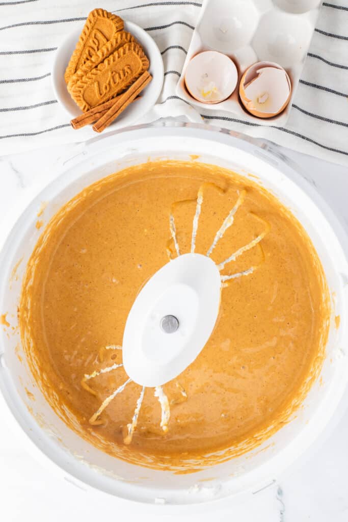 Smooth pumpkin cheesecake batter blended in a mixing bowl and ready to fill the muffin cups.