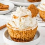 Mini pumpkin cheesecake with Biscoff crust, creamy pumpkin filling, whipped cream, cinnamon, and a Biscoff cookie garnish.