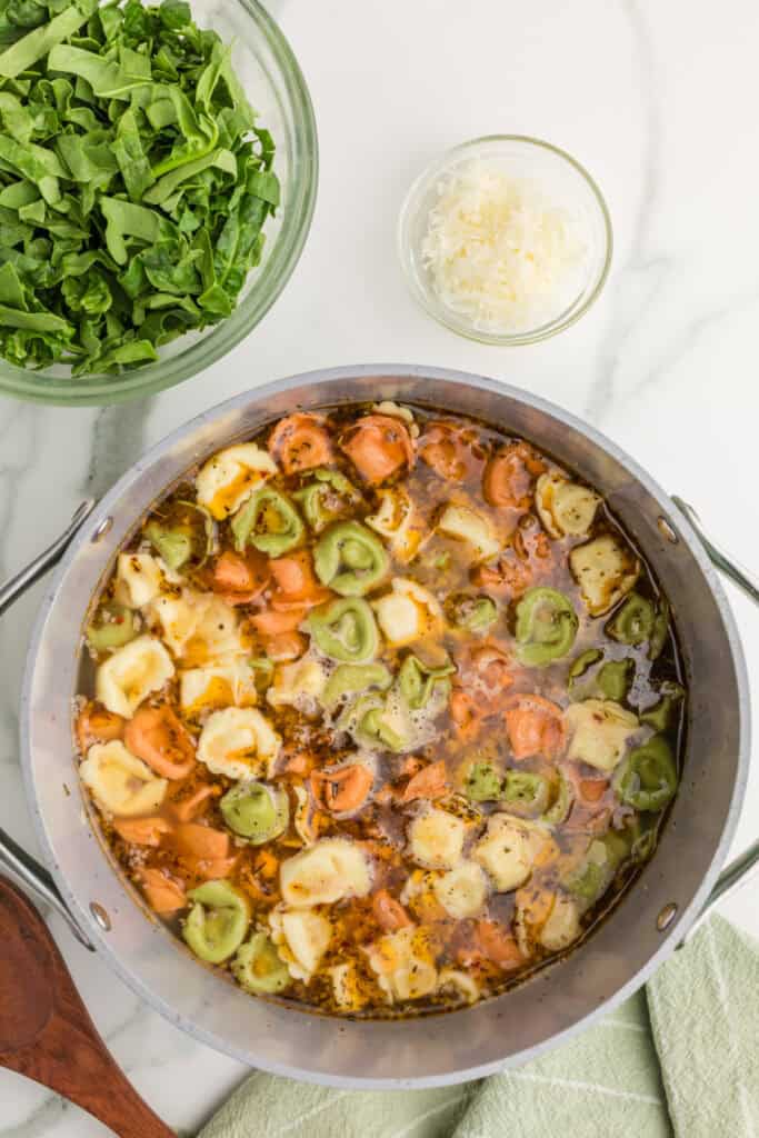 Colorful tortellini cooking with Italian sausage in seasoned chicken broth for an easy one-pot soup.