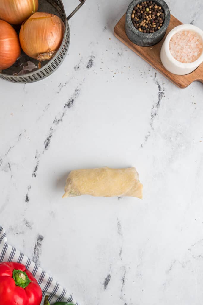 Assembled Philly Cheesesteak Egg Roll tightly rolled and ready for frying