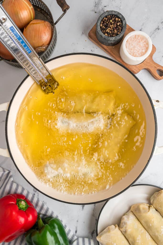 Philly Cheesesteak Egg Rolls frying in hot vegetable oil at 350°F