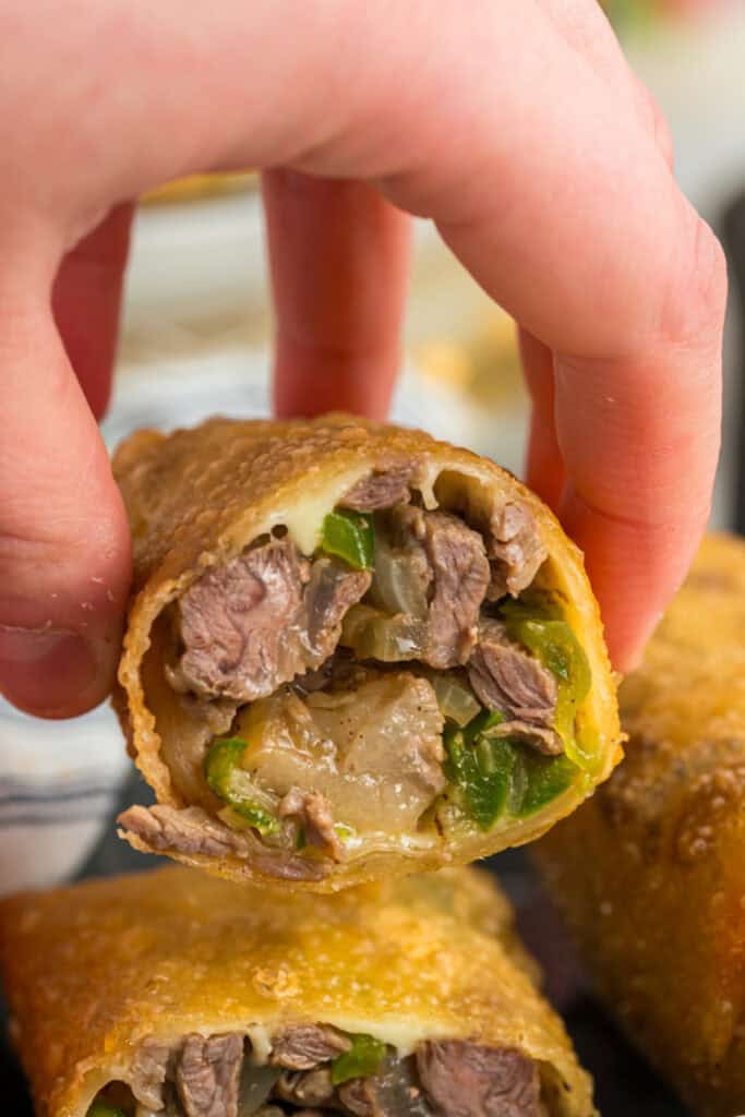 Close-up of a cut Philly Cheesesteak Egg Roll showing steak, green peppers, onions, and melted provolone
