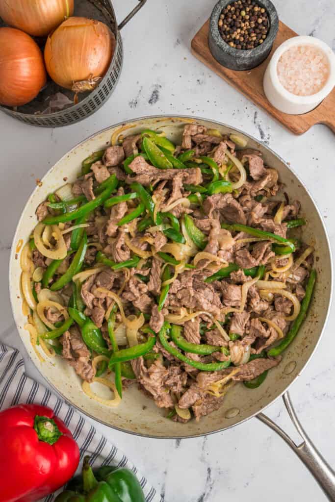 Philly cheesesteak filling made with cooked steak, green peppers, and caramelized onions