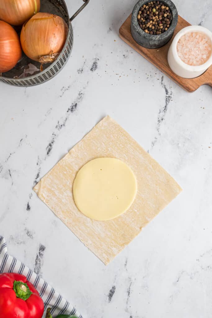 Slice of provolone cheese placed in the center of an egg roll wrapper