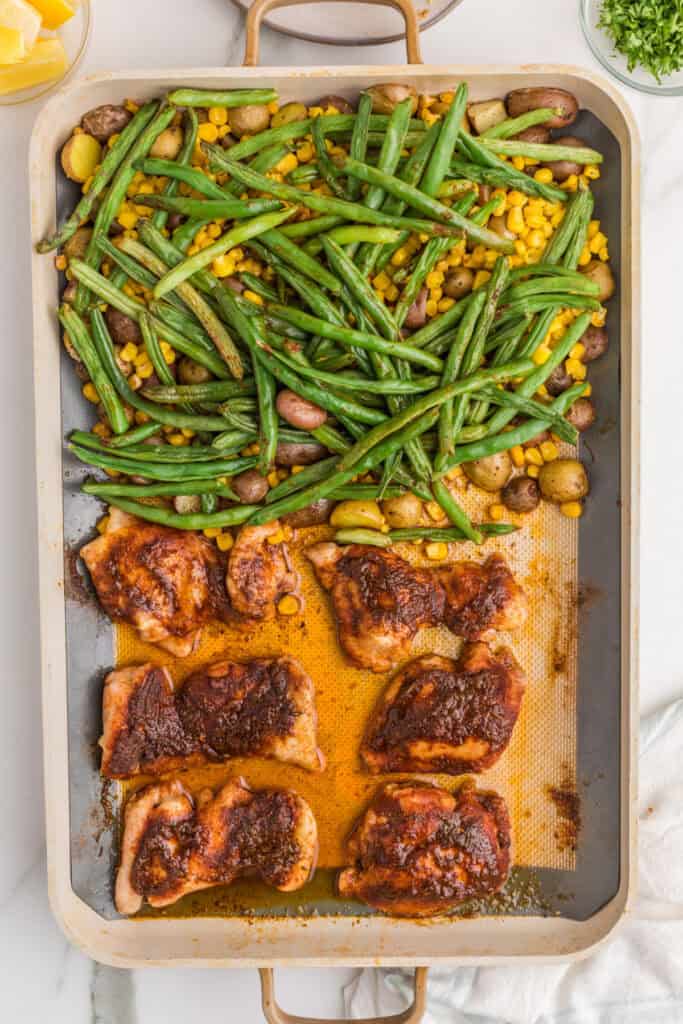 Cooked Sheet Pan Blackened Chicken Thighs with roasted green beans, corn, and baby potatoes.