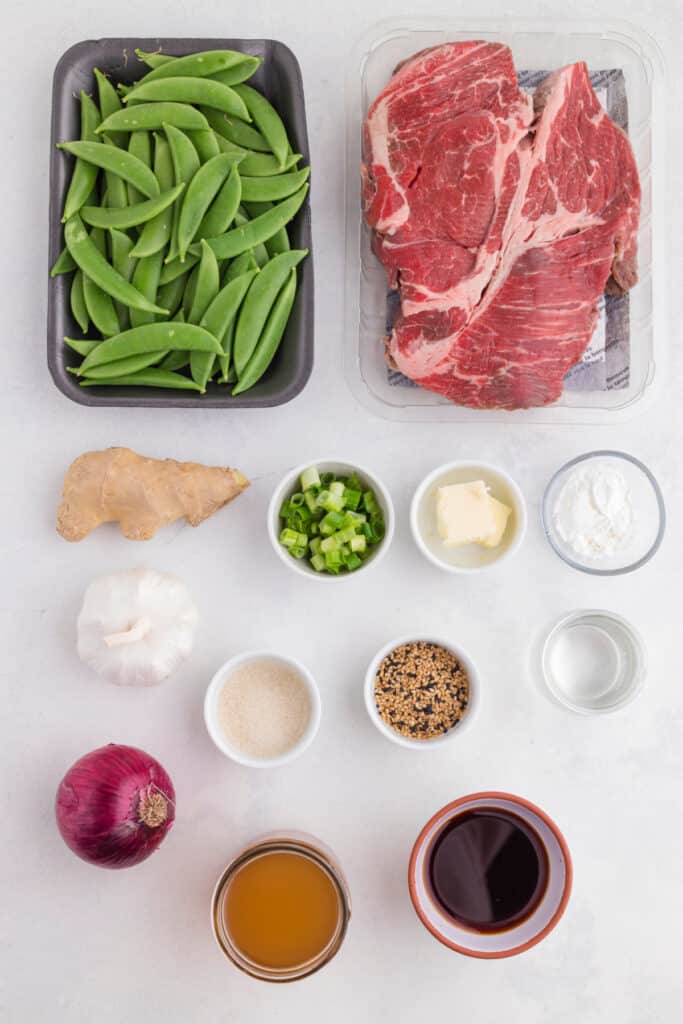 Ingredients for Slow Cooker Asian Pot Roast including chuck roast, snap peas, ginger, garlic, onion, soy sauce, beef stock, and seasonings
