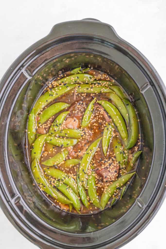 Slow Cooker Asian Pot Roast with snap peas and sesame seeds in the thickened savory sauce
