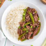 Slow Cooker Asian Pot Roast served over white rice with tender beef, snap peas, green onions, and sesame seeds