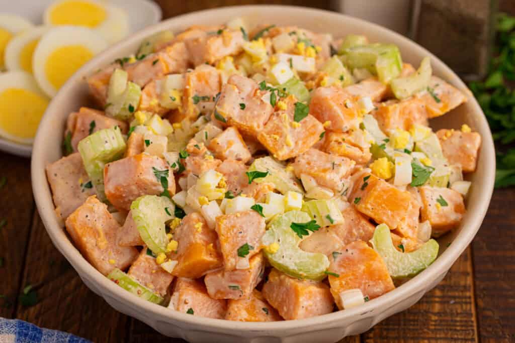 Bowl of Southern-style Sweet Potato Salad with creamy sweet potatoes, hard-boiled eggs, celery, onion, and parsley