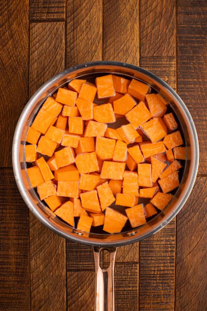 Peeled sweet potato cubes cooking in a pot of salted water until fork tender
