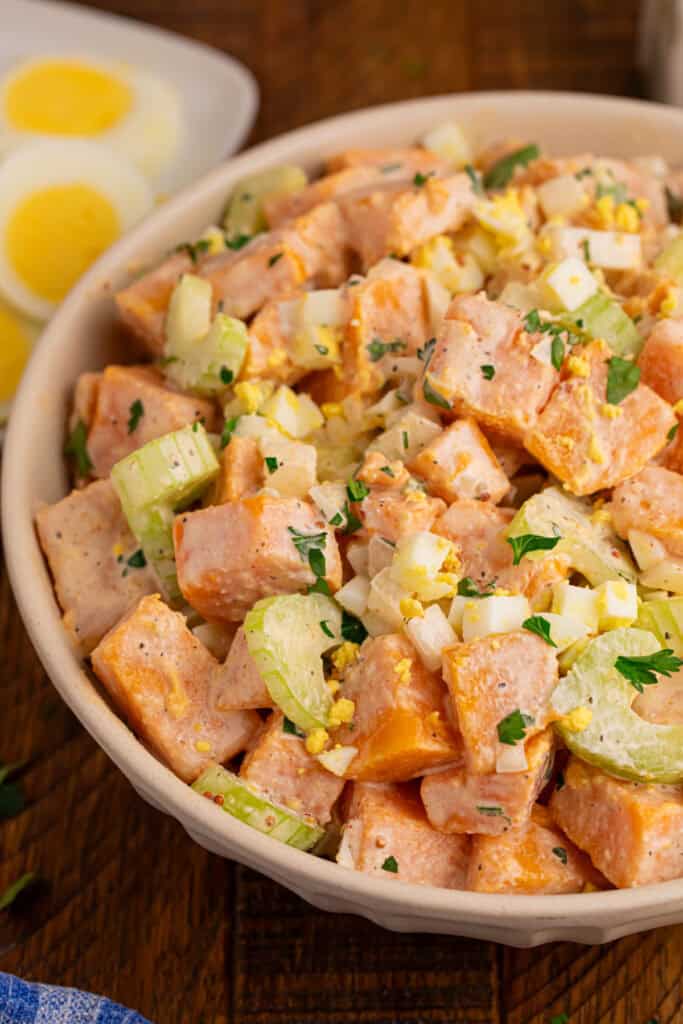 Close-up of creamy Sweet Potato Salad with tender sweet potatoes, celery, chopped eggs, onion, and fresh parsley