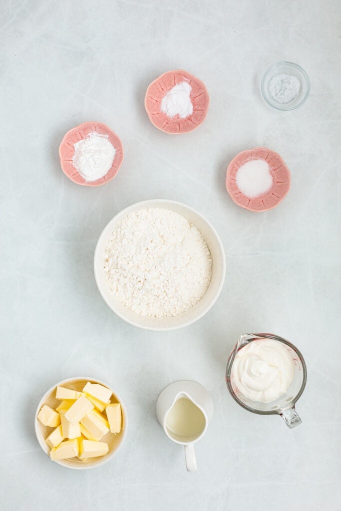 Ingredients for air fryer sour cream biscuits arranged on a light work surface.