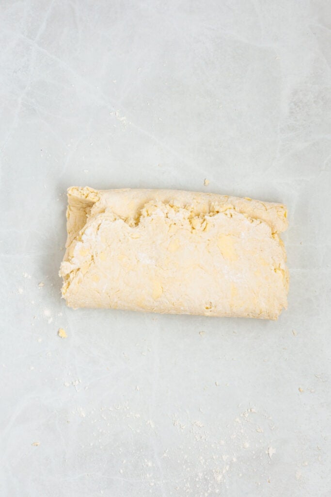 Sour cream biscuit dough folded into a rectangle on a lightly floured work surface.