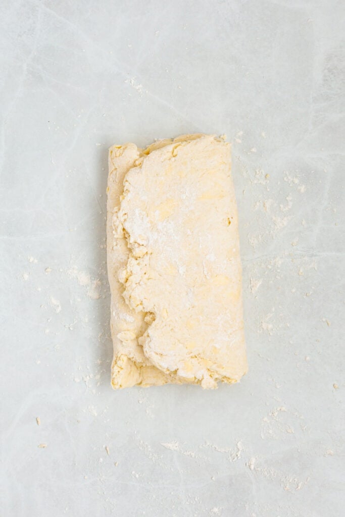 Biscuit dough folded lengthwise during the layering process for flaky air fryer biscuits.
