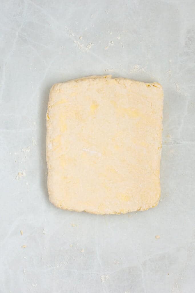 Sour cream biscuit dough rolled into an even rectangle and ready to be cut.