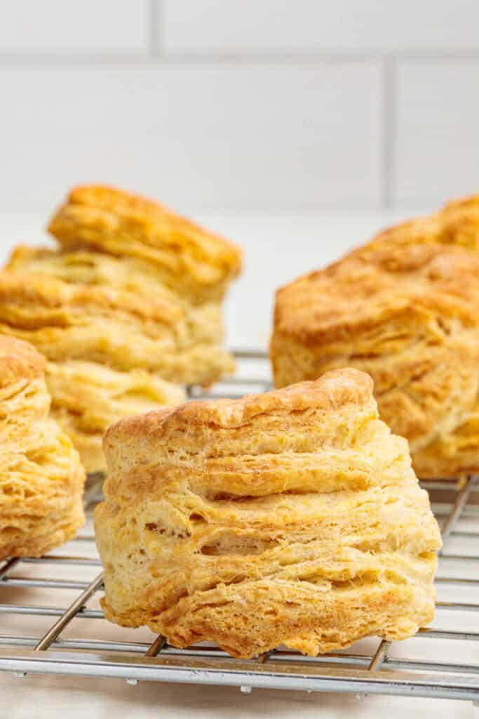 Close-up of golden air fryer sour cream biscuits showing their tall, flaky layers on a cooling rack.