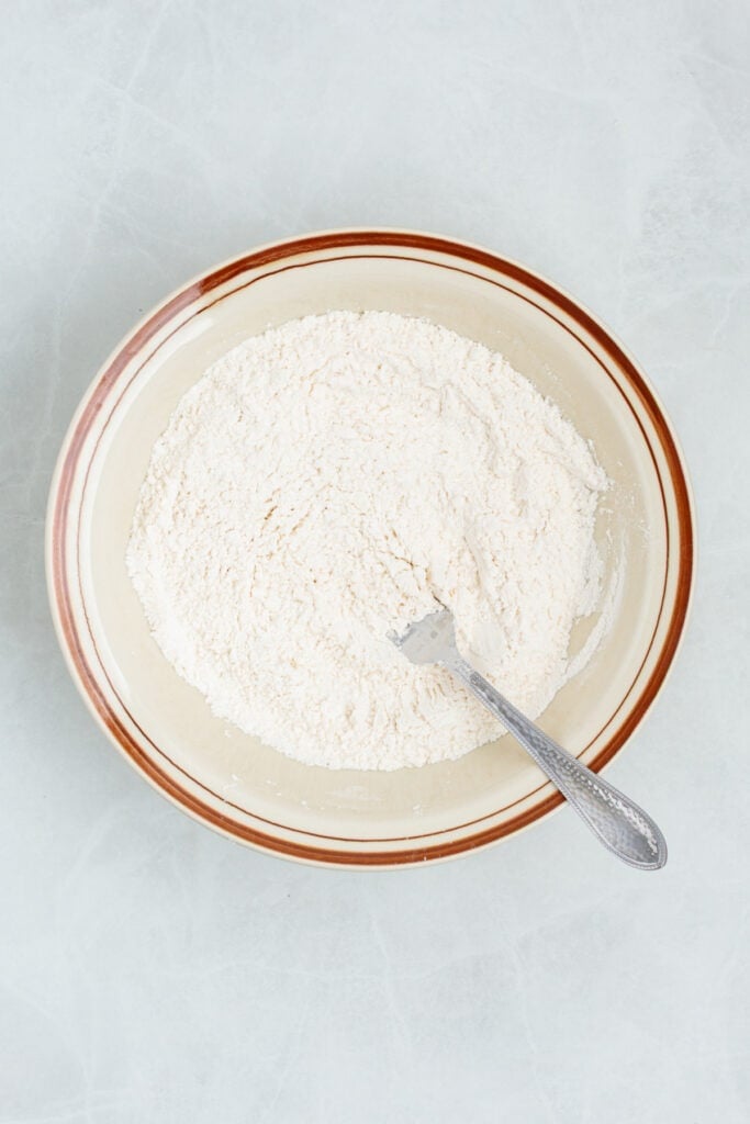 Flour mixture for sour cream biscuits in a large mixing bowl being mixed.