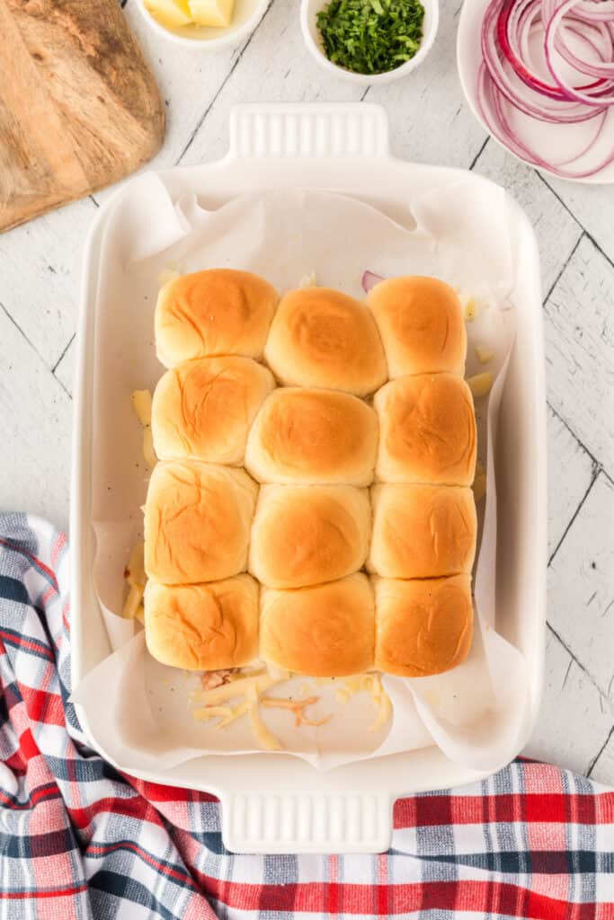 Slider bun tops placed over the BBQ chicken, cheese, and red onion filling before baking.