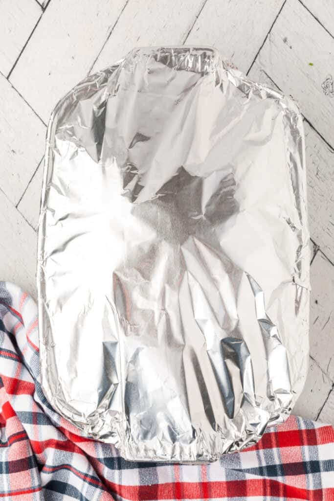 Baking dish covered with aluminum foil for the first stage of baking the chicken sliders.