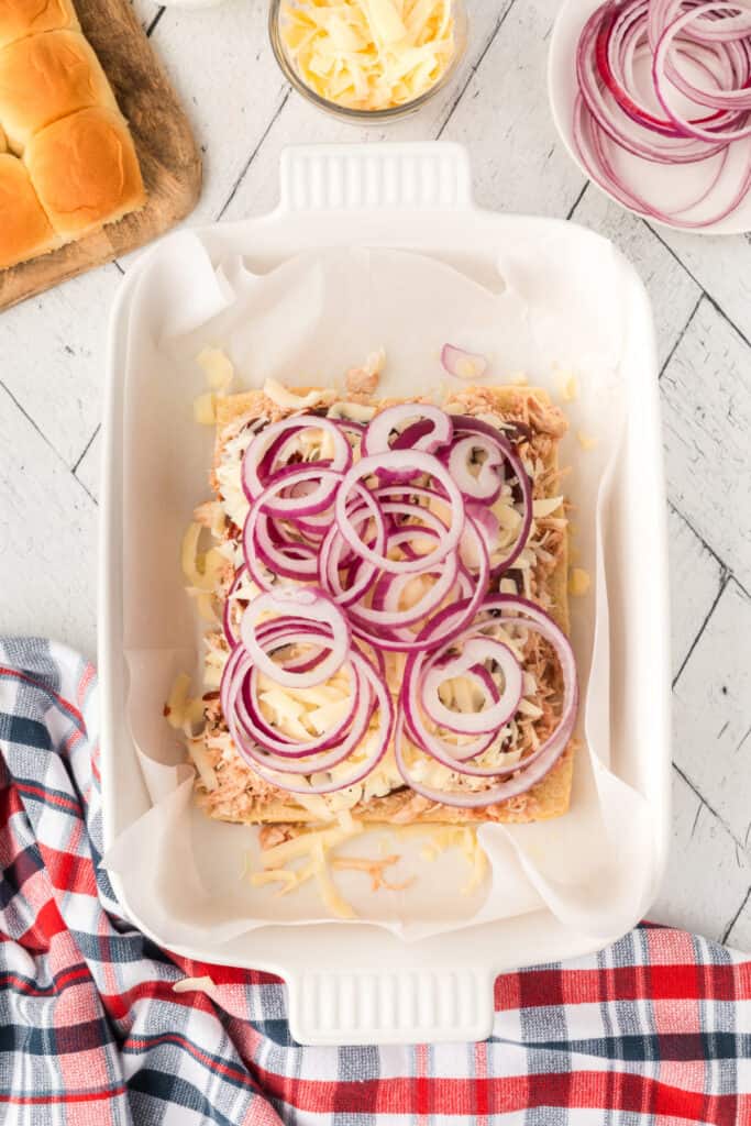Thinly sliced red onion layered over cheese and BBQ chicken for the sliders.