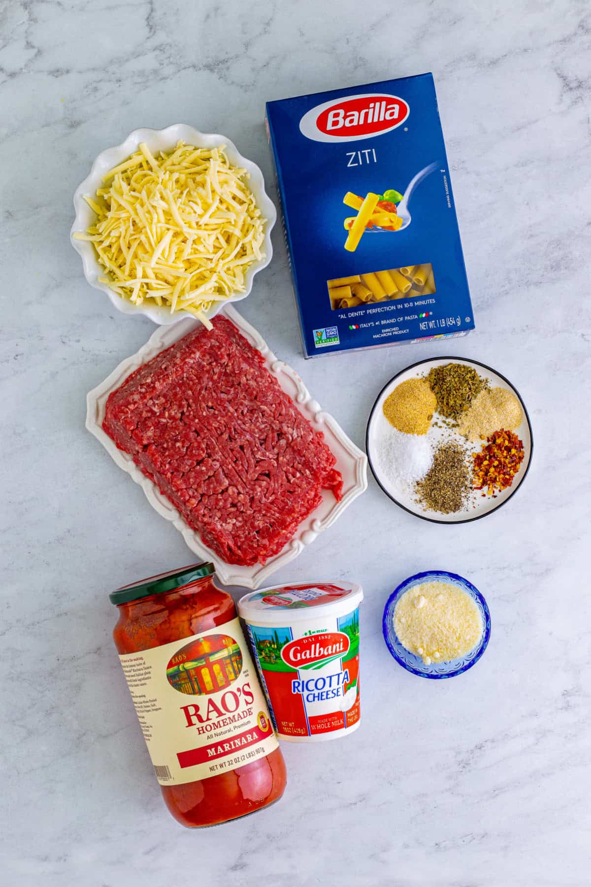 Ingredients for baked ziti including pasta, ground beef, sauce, ricotta and mozzarella