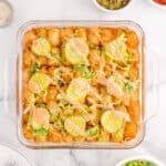 Overhead view of Big Mac Tater Tot Casserole topped with crispy tater tots, dill pickles, shredded lettuce, burger sauce, and sesame seeds.