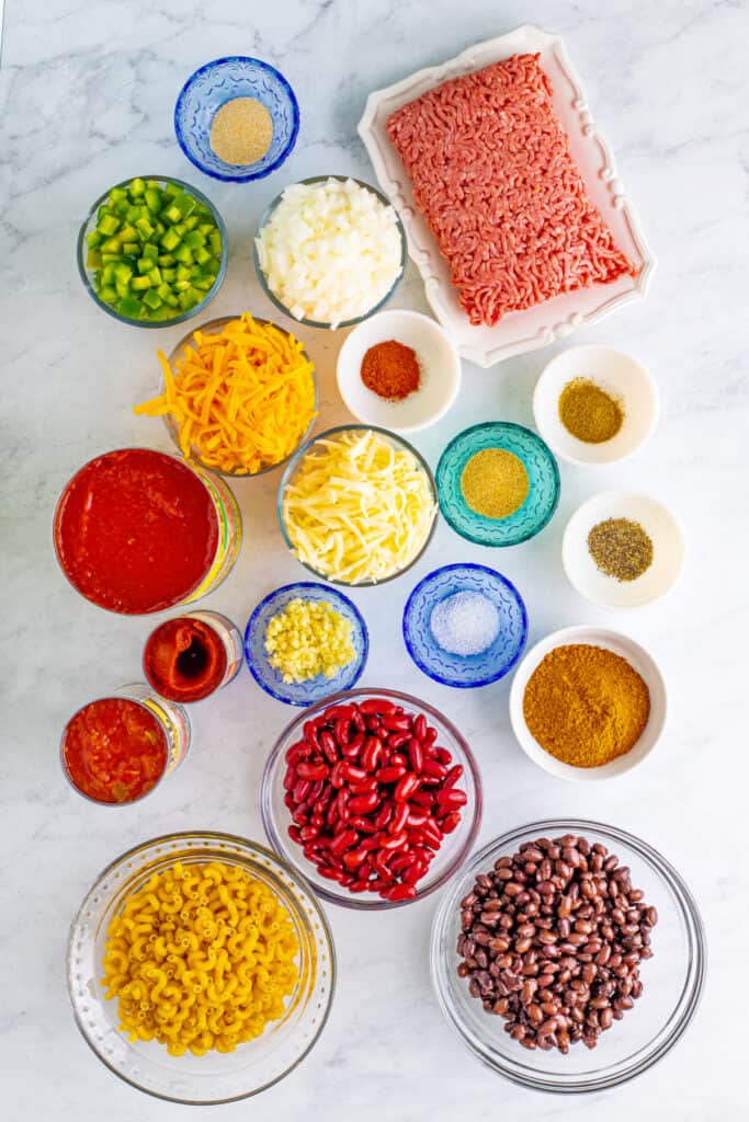 Chili Mac ingredients including ground beef, elbow macaroni, beans, tomatoes, peppers, onion, cheese, garlic, and seasonings