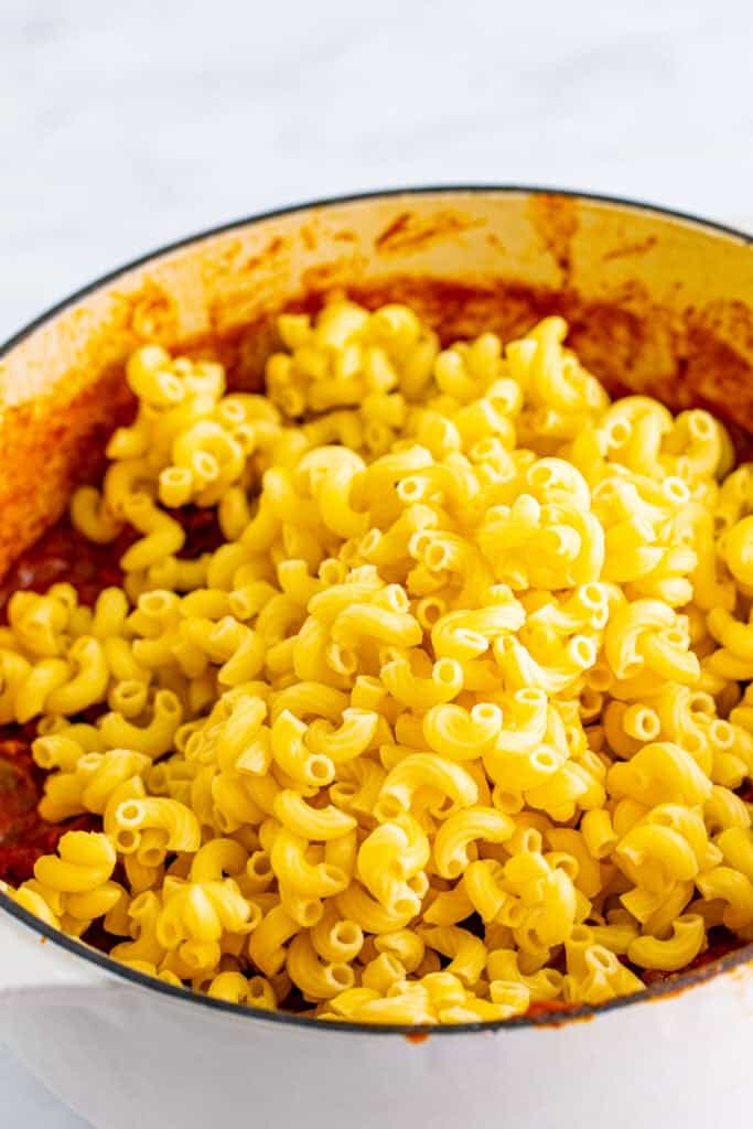 Cooked elbow macaroni added to homemade beef and bean chili