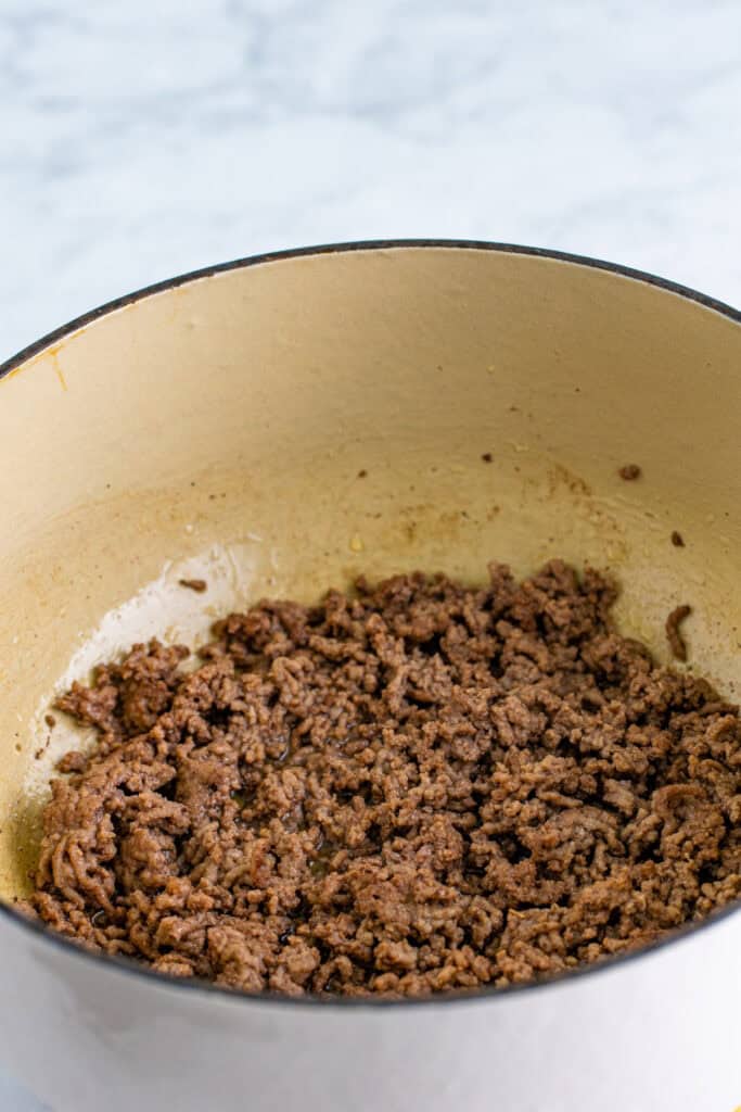 Ground beef browning in a Dutch oven for homemade Chili Mac
