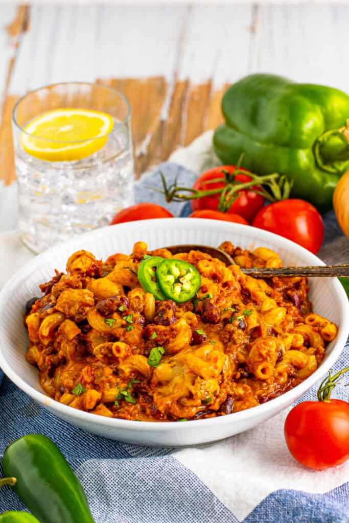 Bowl of cheesy Chili Mac with ground beef, beans, elbow macaroni, and sliced jalapeño garnish