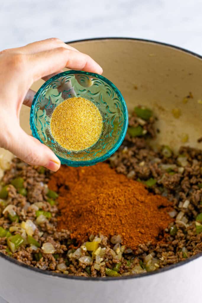 Garlic powder being added to the seasoned ground beef mixture for Chili Mac