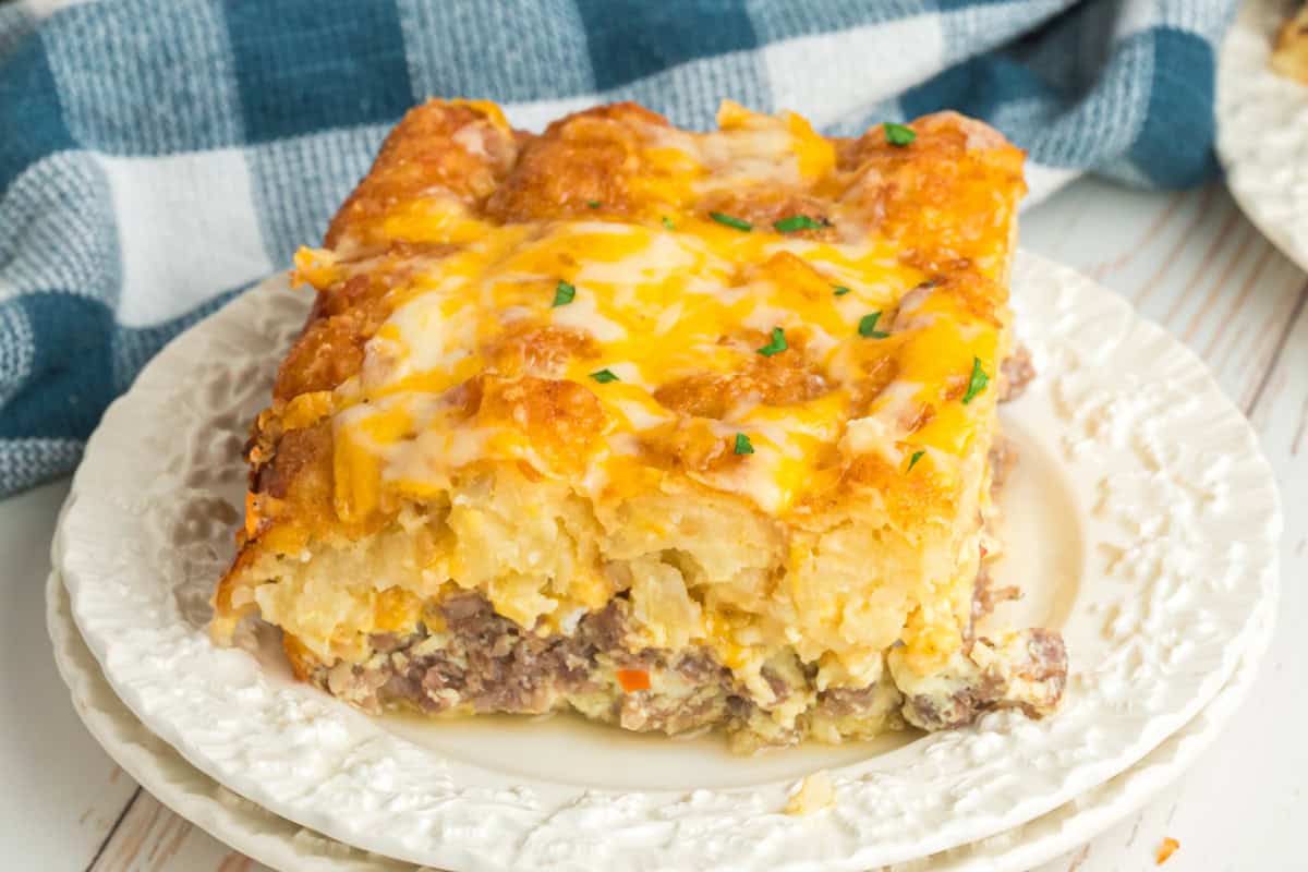 Breakfast tater tot casserole slice showing layers of sausage, eggs, and cheese-topped tots.