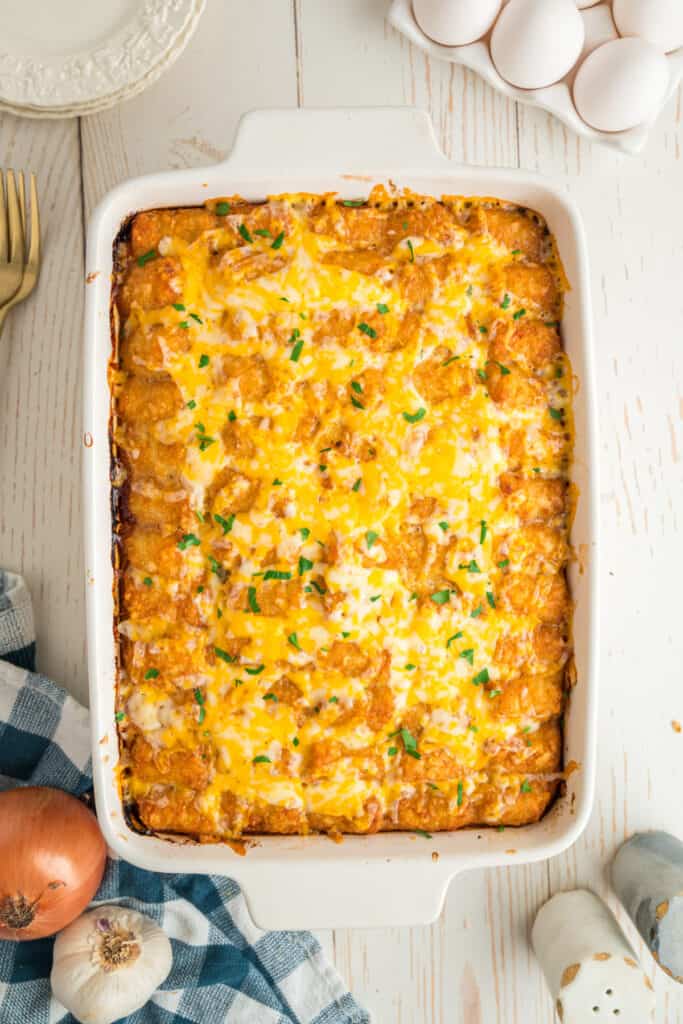 Baked breakfast tater tot casserole with melted cheese and a green herb garnish.