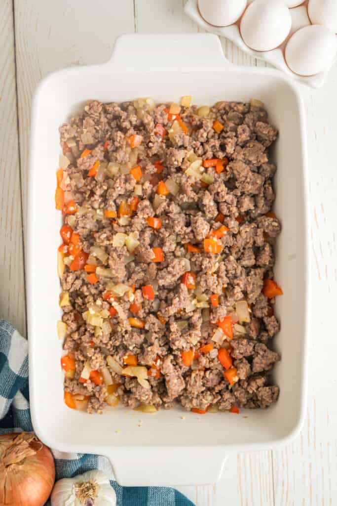 Cooked sausage mixture spread in a white baking dish.